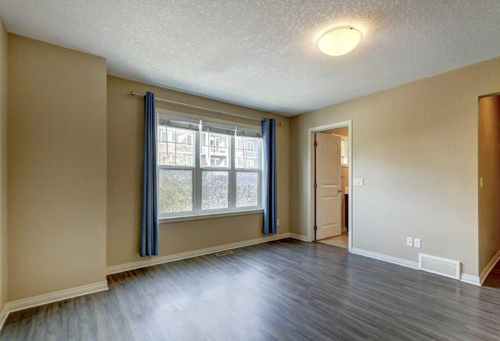 Empty beige room with gray floor, window with blue curtains, and open doorway