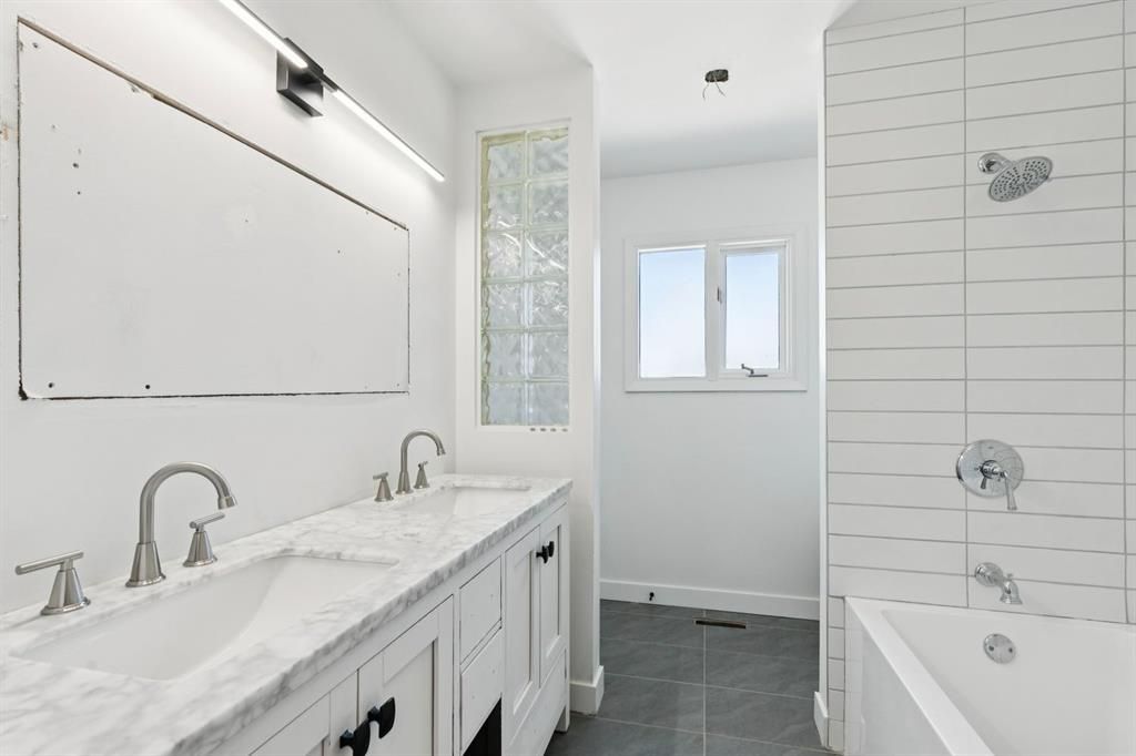 Bright white bathroom with double sink vanity, large mirror, shower, and bathtub