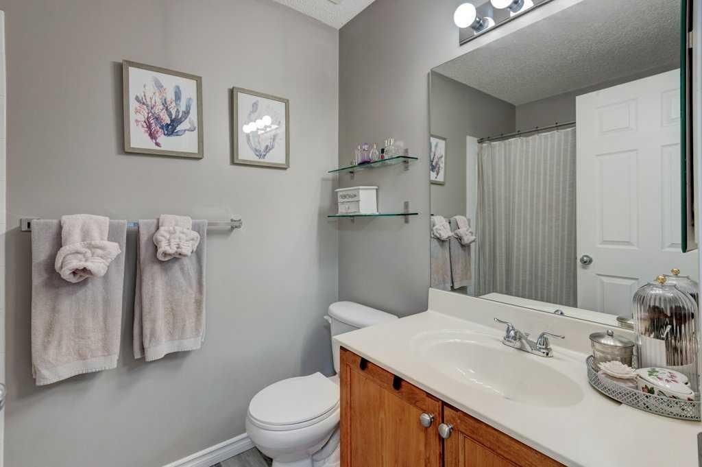 Modern bathroom with vanity, mirror, tub, gray walls, white towels, and wooden cabinets