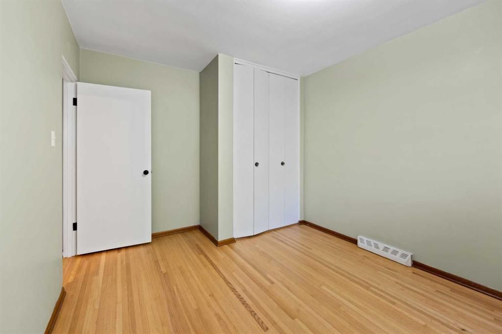 Empty light-green room with hardwood floor and two white closet doors