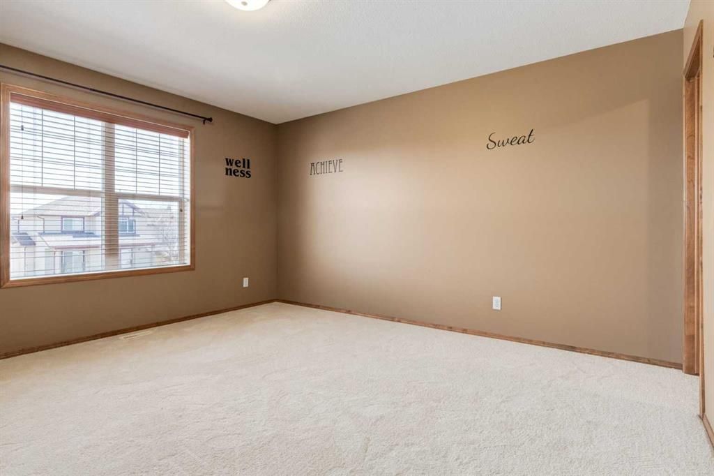Empty beige carpeted bedroom with a window and tan walls