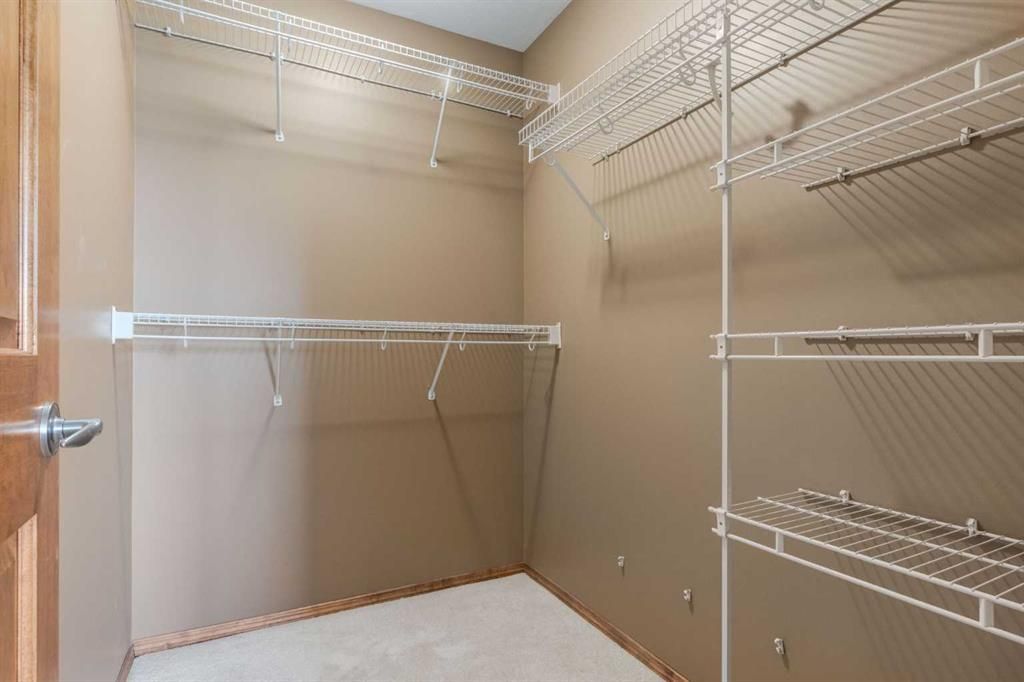 Empty beige walk-in closet with wire shelving and hanging rods.