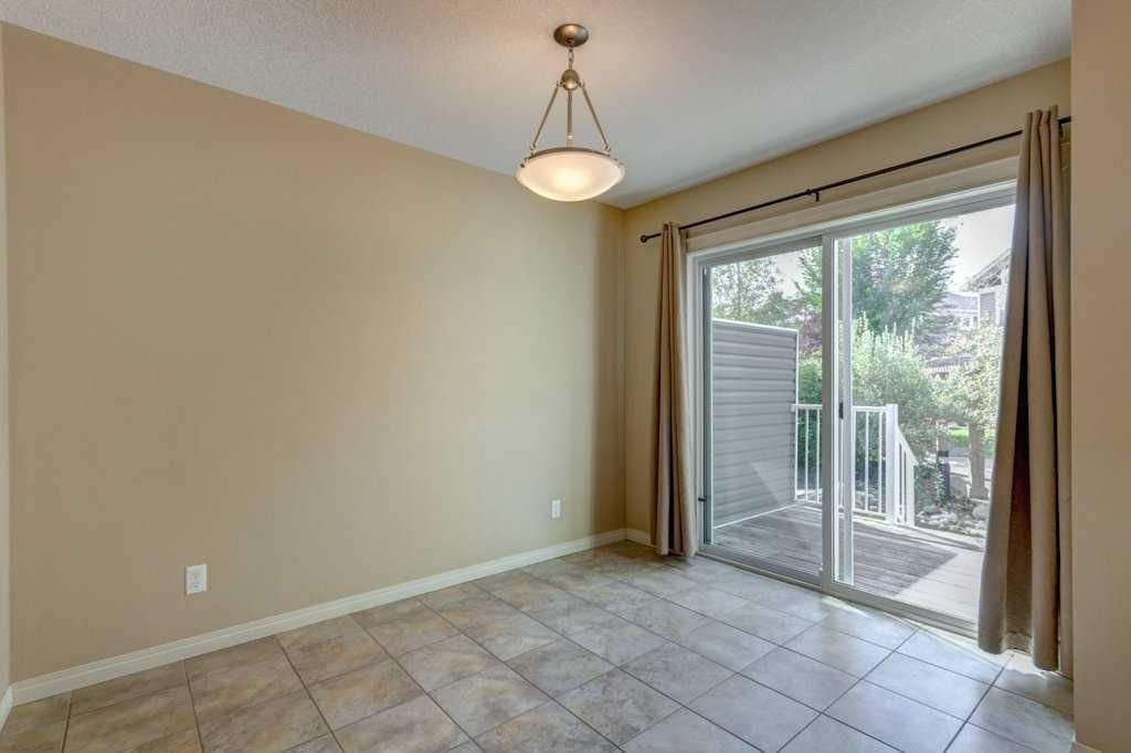 Empty beige room with tiled floor, ceiling light, and sliding glass door to a patio