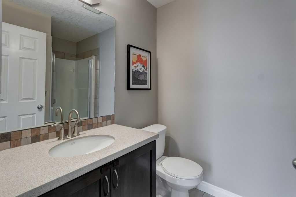 Laundry closet with stacked washer and dryer beside an open white door.