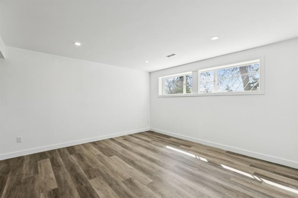 Empty white room with wood-look floors and a small window.
