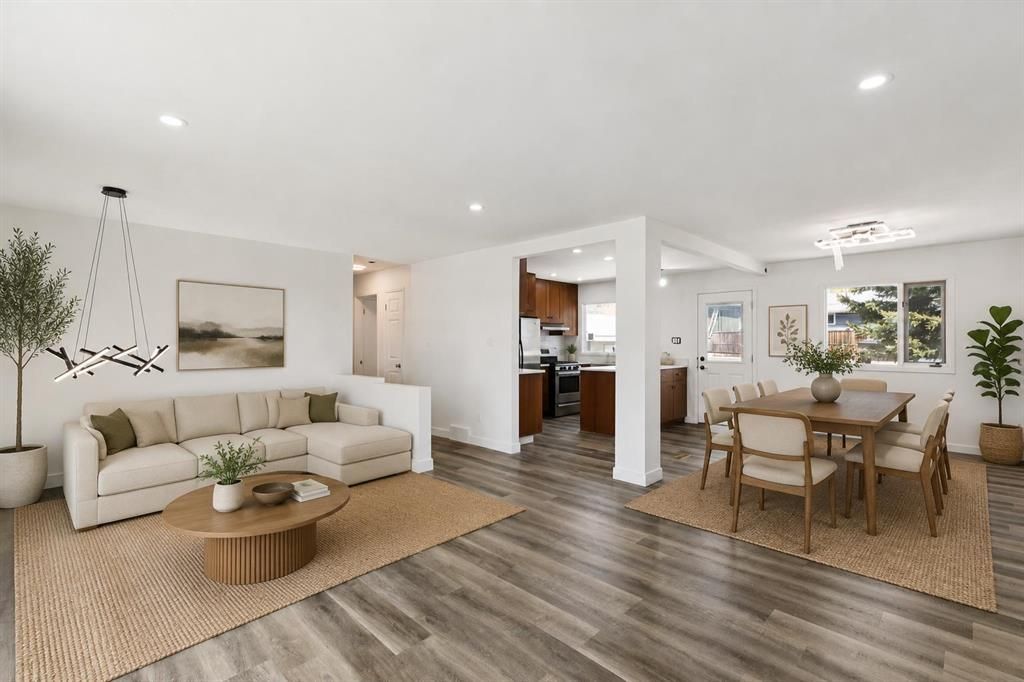 Bright open-concept living and dining room with white walls, wood floors, and beige furniture