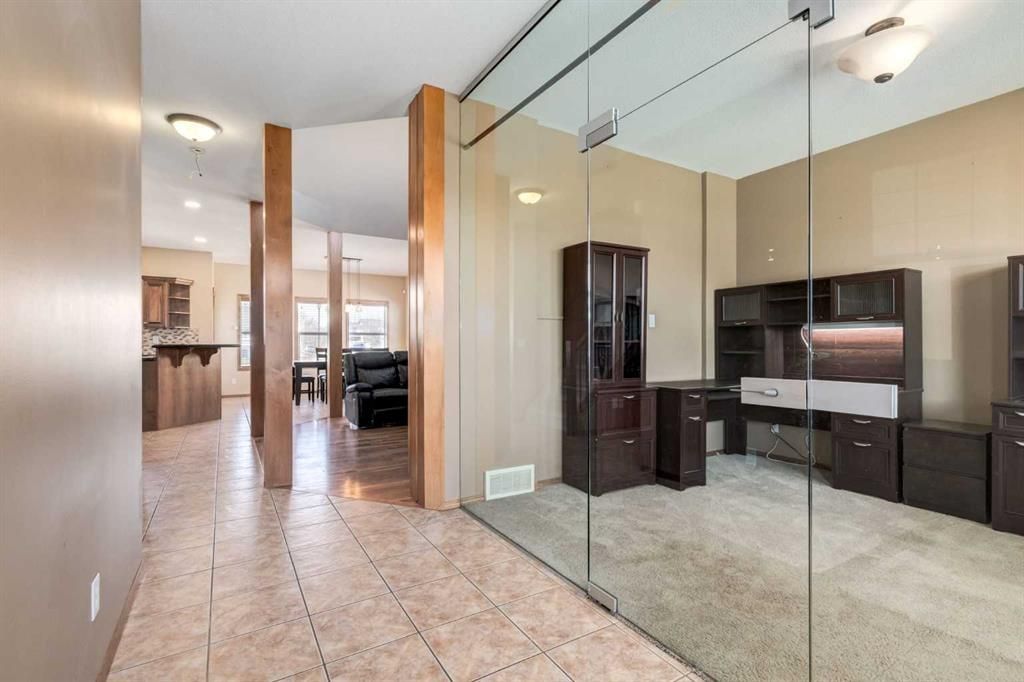 Modern living room with glass partition, tiled floor, and TV entertainment center