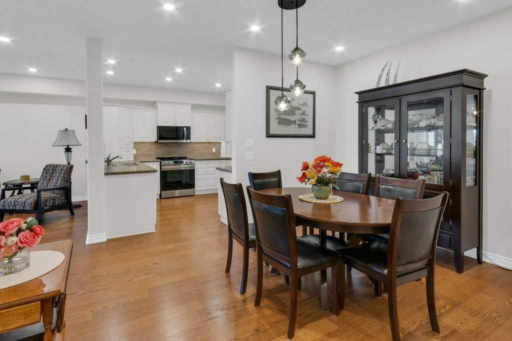 Open-concept dining room and kitchen with wooden table, dark chairs, cabinet, and hardwood floors.