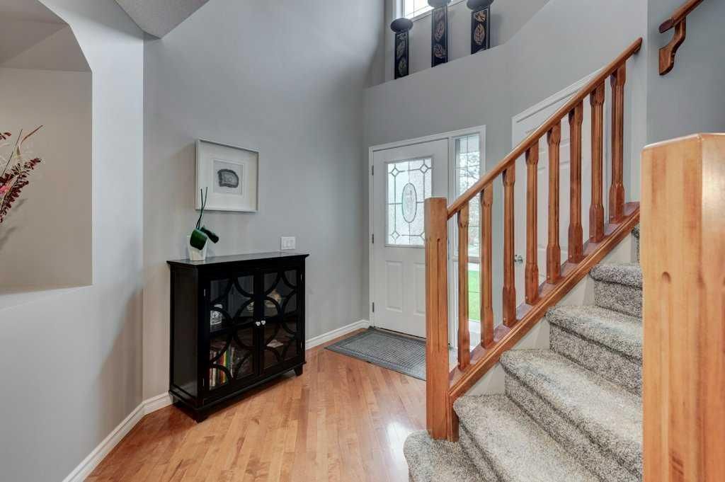 Bright entryway with wood stairs, black cabinet, and front door with frosted glass paneling.