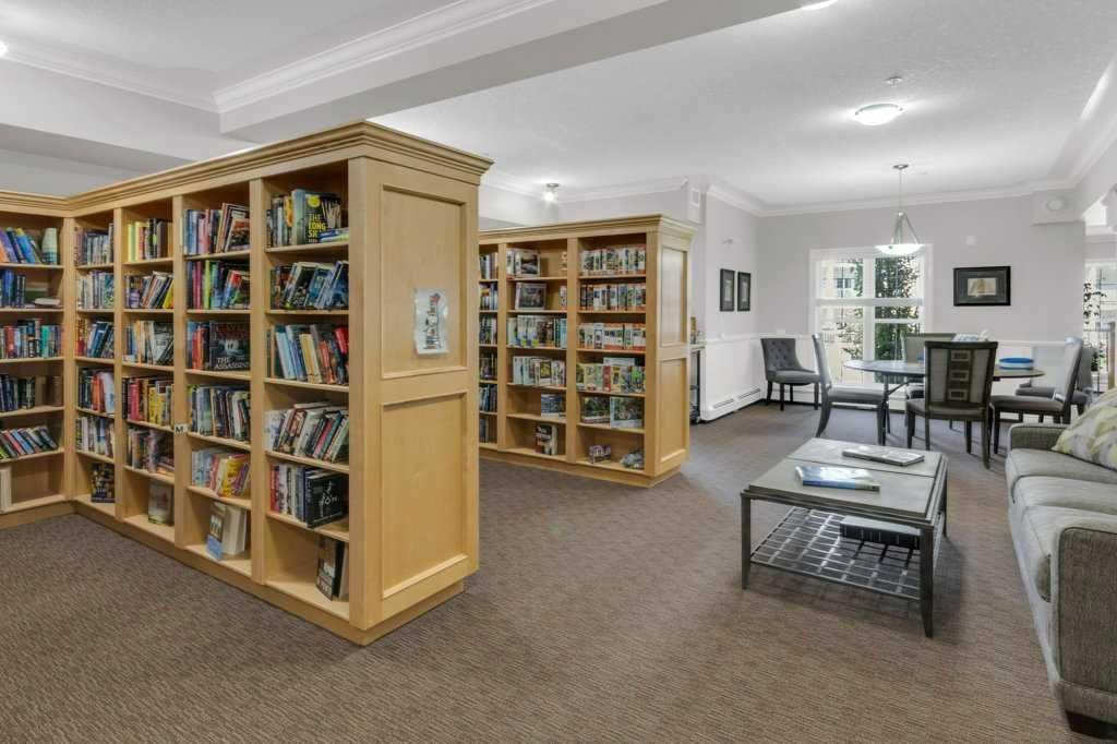 Bright living room with wooden bookshelves, gray sofa, coffee table, and dining area in the background