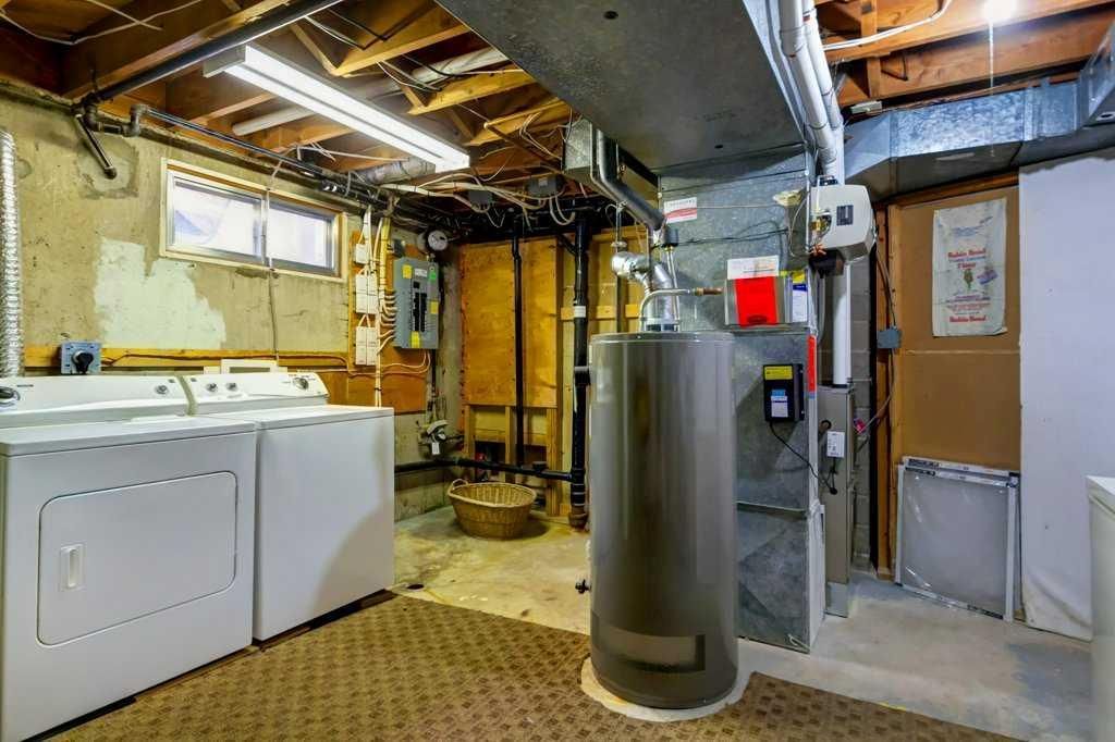 Basement laundry room with washer, dryer, water heater, and exposed ceiling pipes