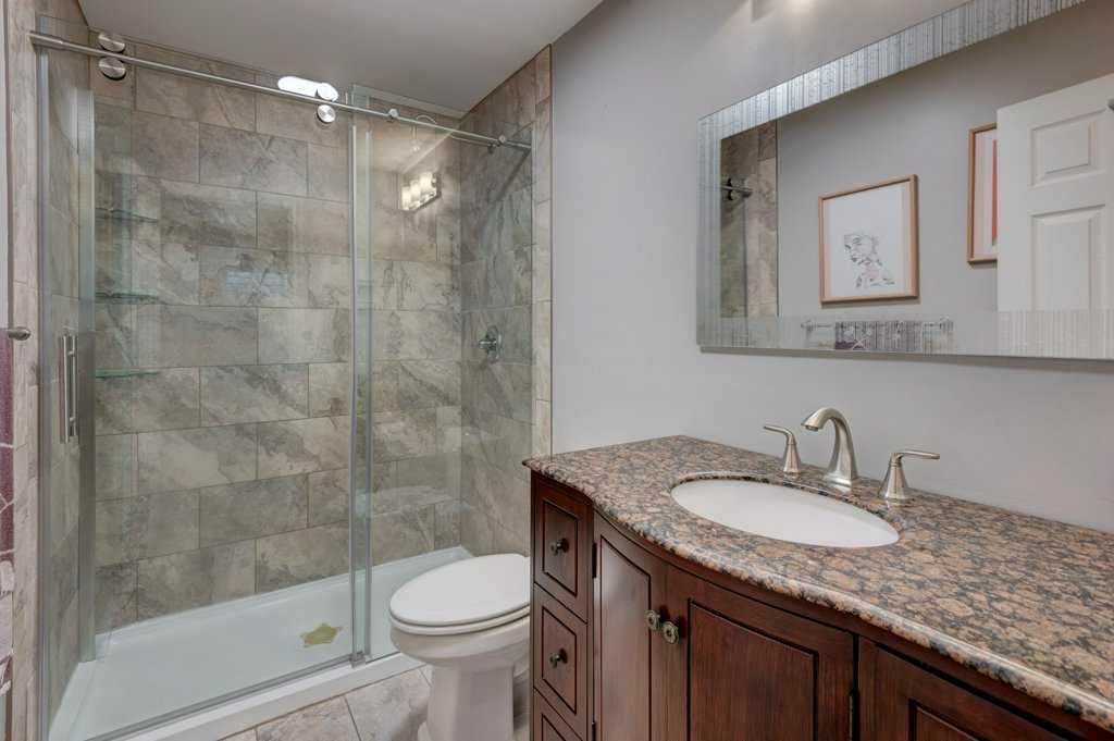 Bathroom with glass shower, toilet, and granite vanity with large mirror