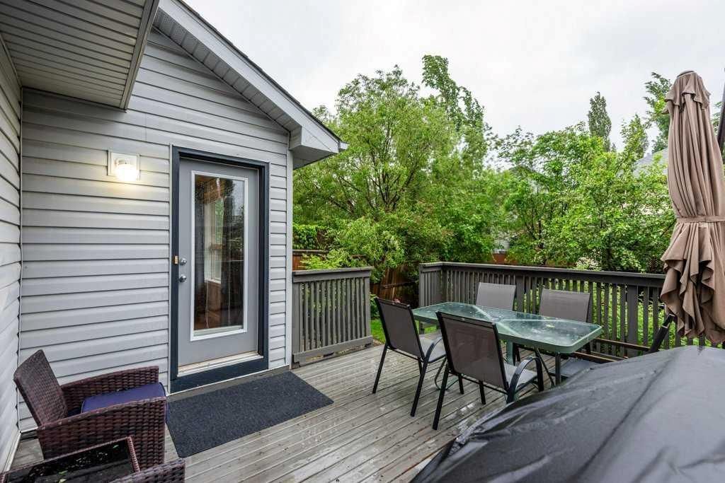 Deck with patio furniture beside a gray house, overlooking trees and a railing