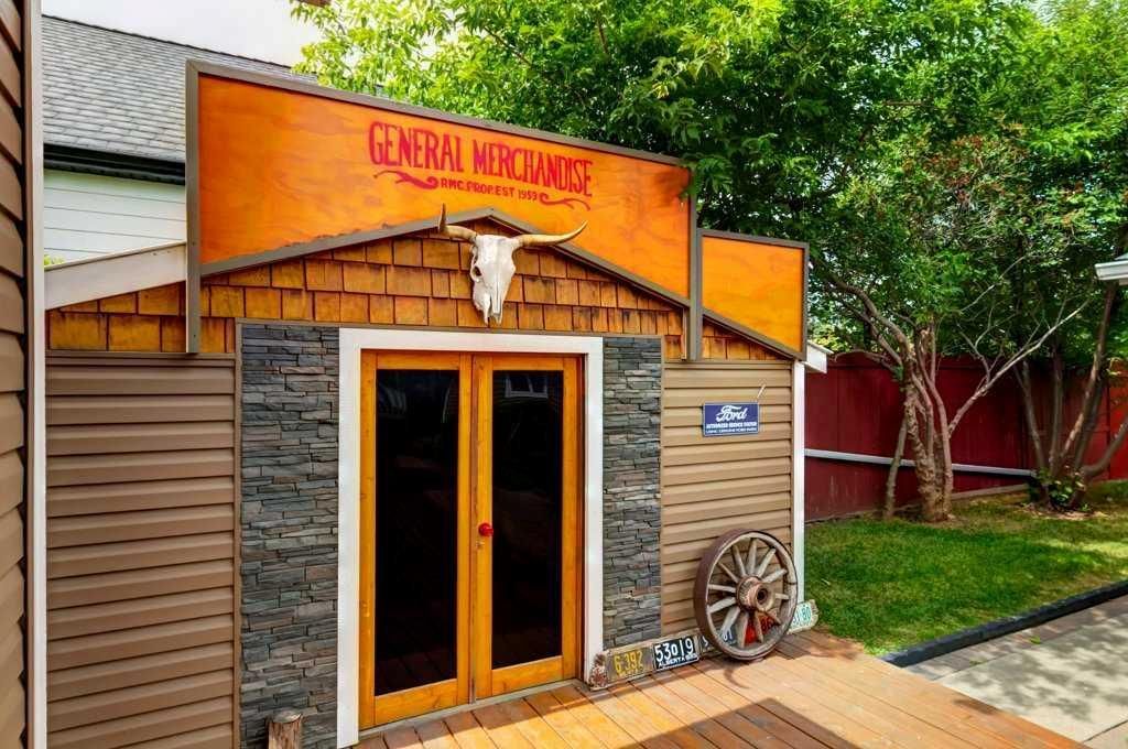 Western storefront with double wooden doors, wagon wheel decor, and stone trim beneath orange signage