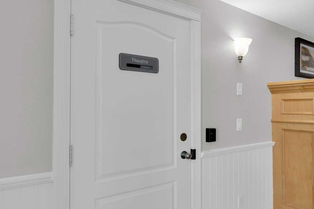White interior door with a small mail slot and black doorknob in a hallway with wainscoting and wall sconce.