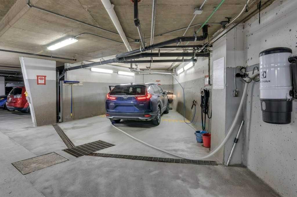Underground parking garage with a blue SUV and exposed utility pipes overhead.