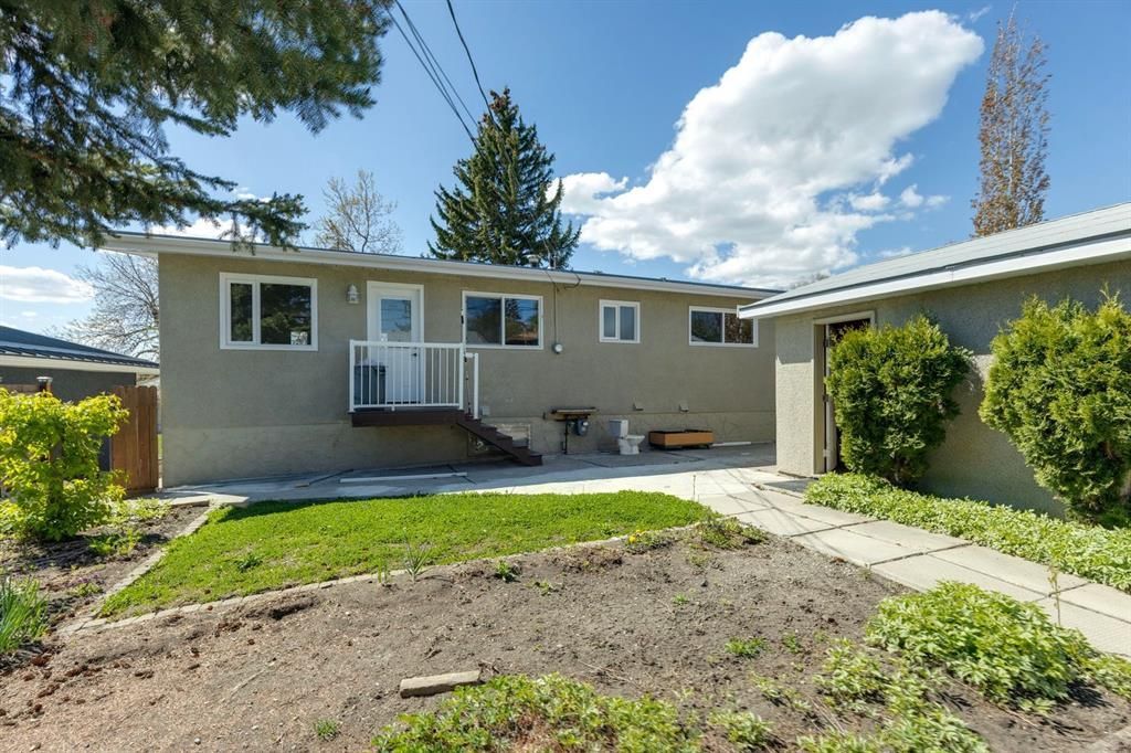 Suburban house with beige siding, front steps, and a grassy yard under a bright blue sky
