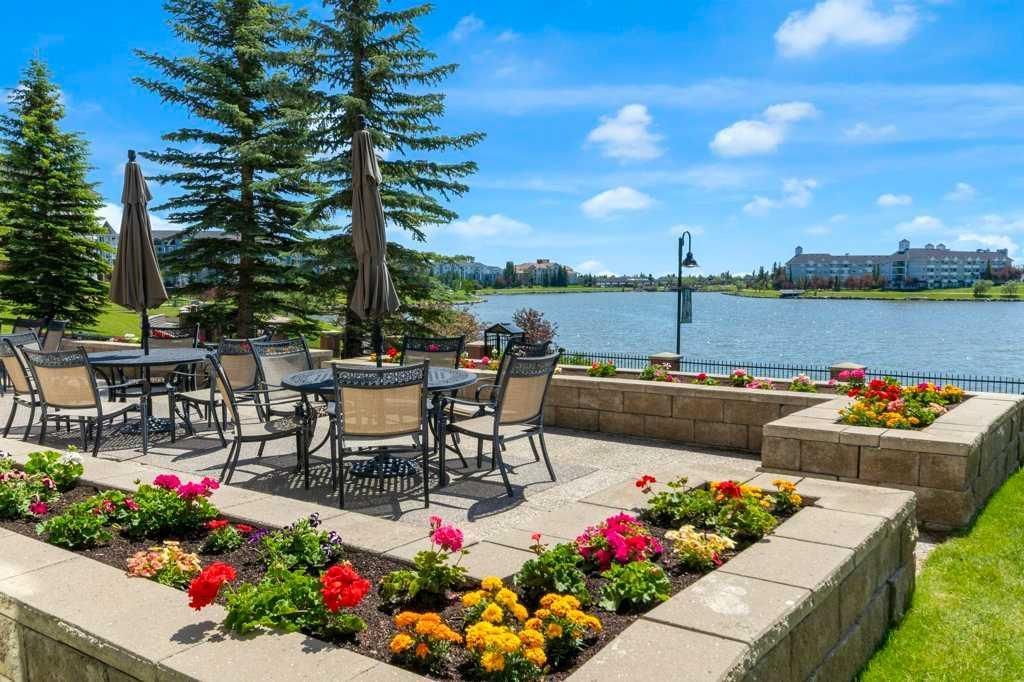 Patio seating with flowers overlooking a lake and city skyline on a sunny day