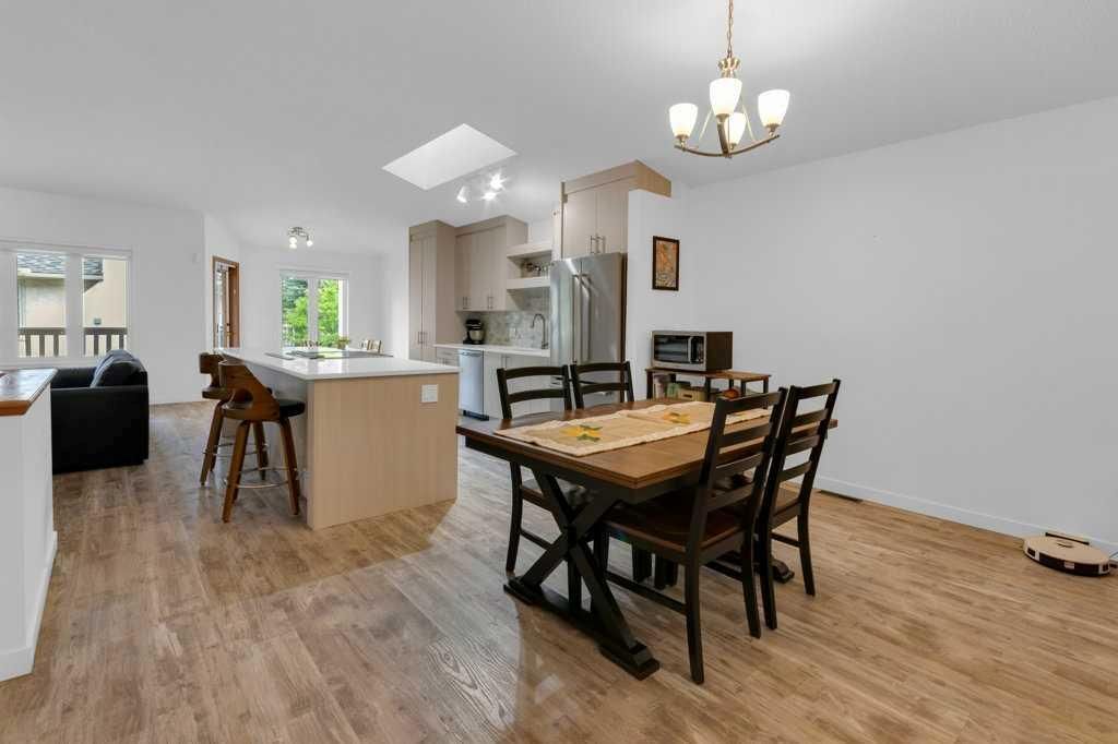 Open-plan dining and kitchen area with wooden table, chairs, island, and white walls