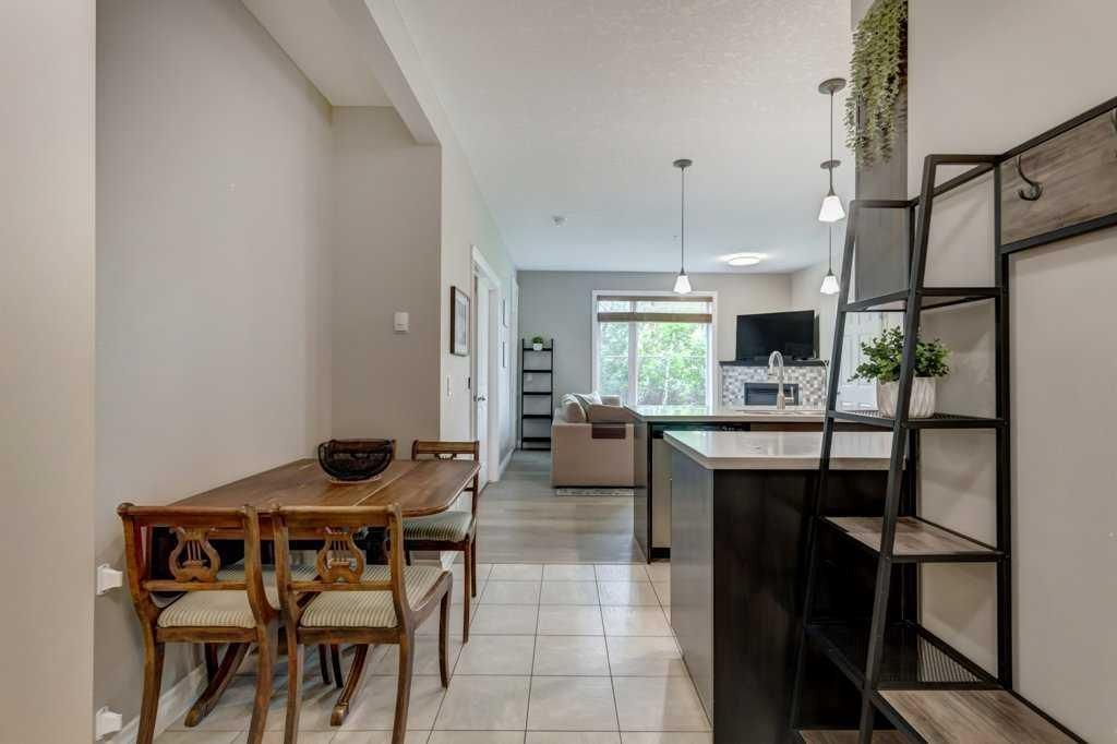 Modern open kitchen and living room with island, pendant lights, gray cabinets, and large windows