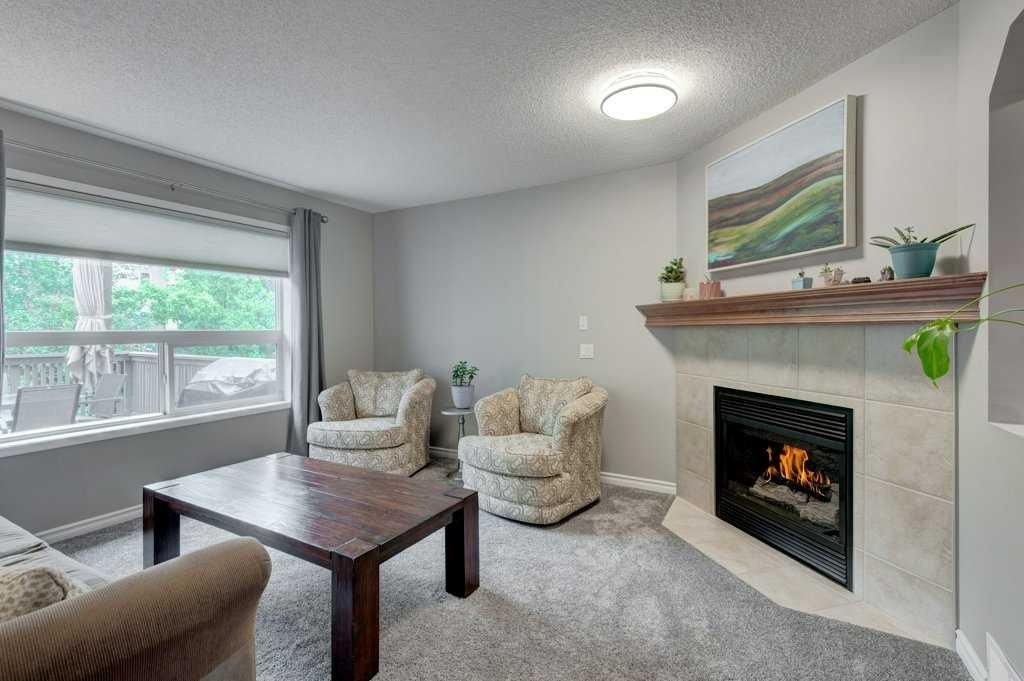 Cozy living room with fireplace, two armchairs, coffee table, and large window view