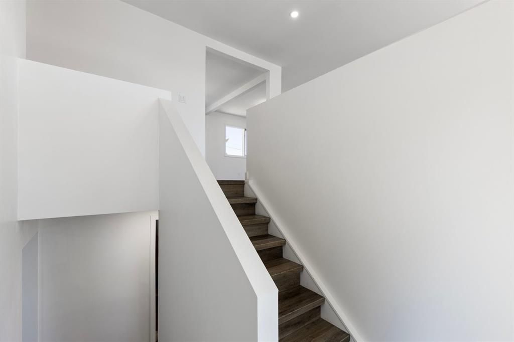 Bright hallway with carpeted stairs and white walls leading to an upper landing