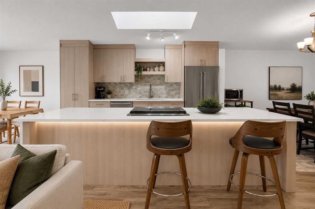 Modern kitchen with light wood cabinets, island seating, and a neutral open-plan living space
