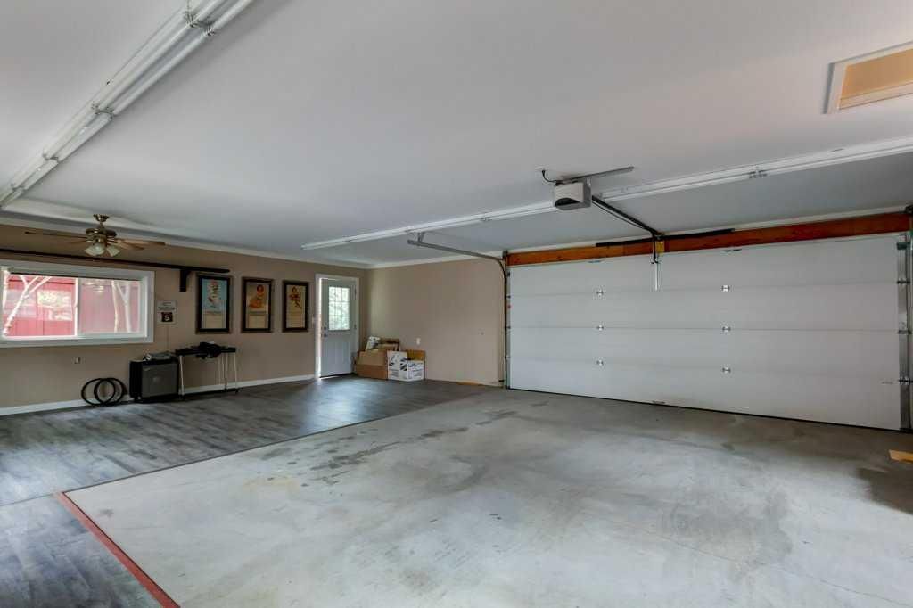 Empty garage with concrete floor, white overhead door, windows, and framed pictures on the left wall