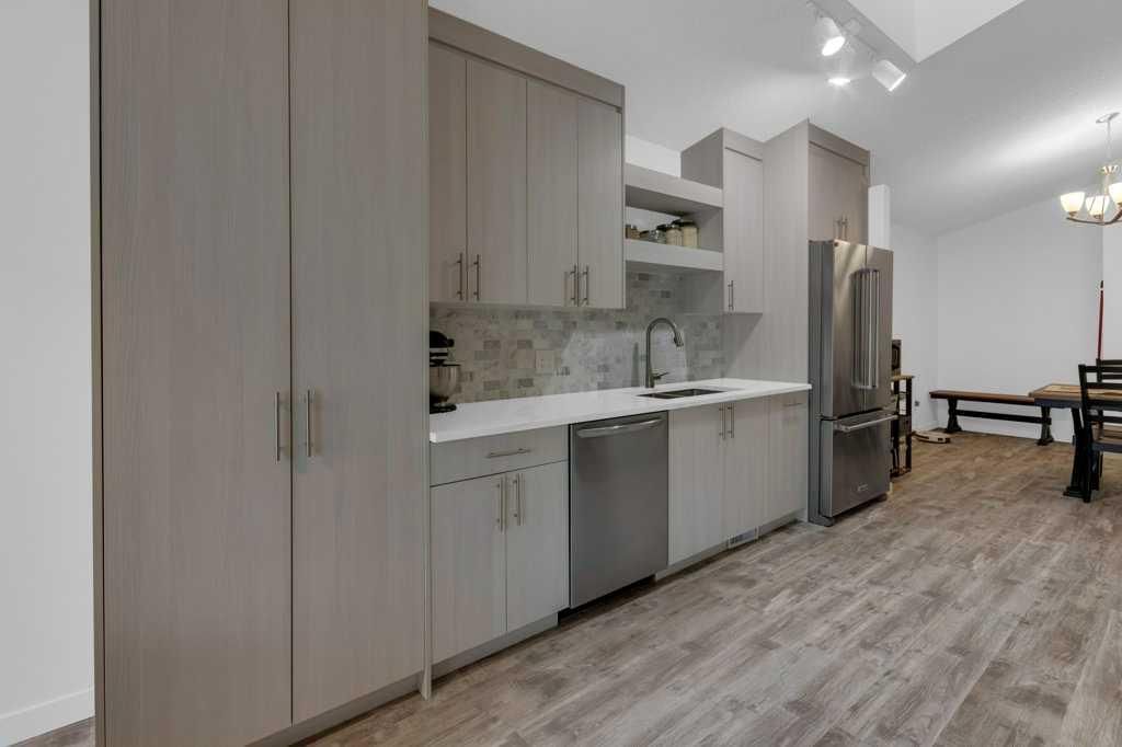 Modern kitchen with wood cabinets, white countertop, stainless dishwasher, and light wood flooring