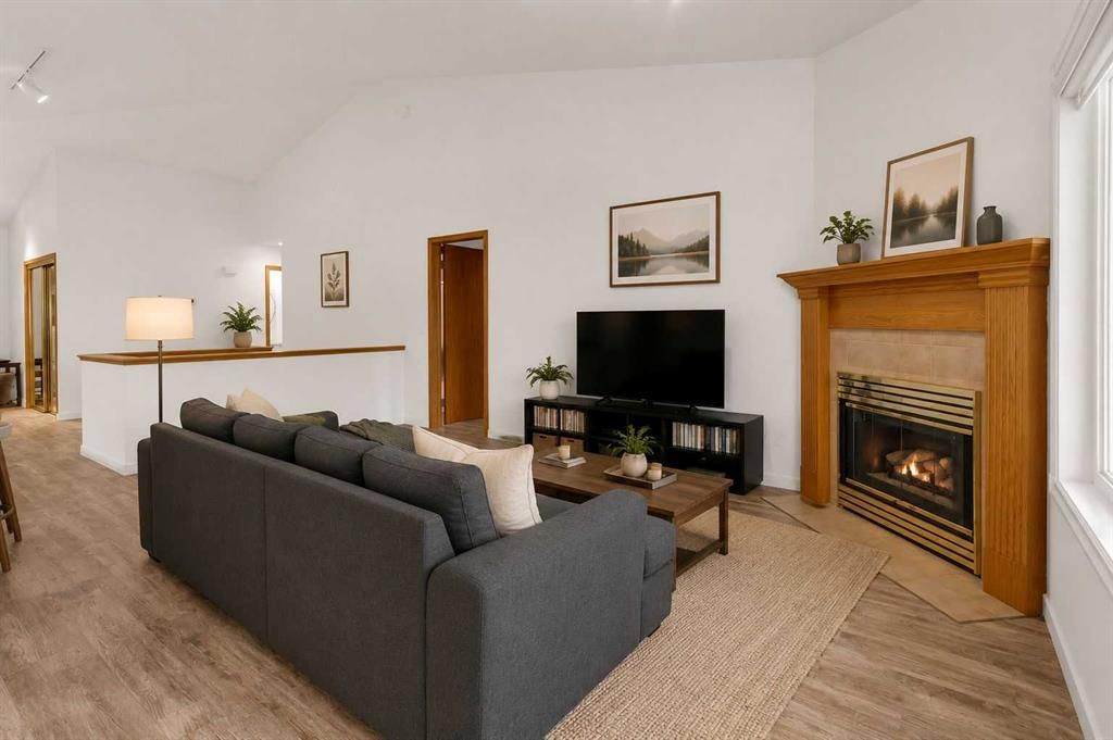 Modern living room with gray sectional sofa, TV, and two fireplaces on white walls.