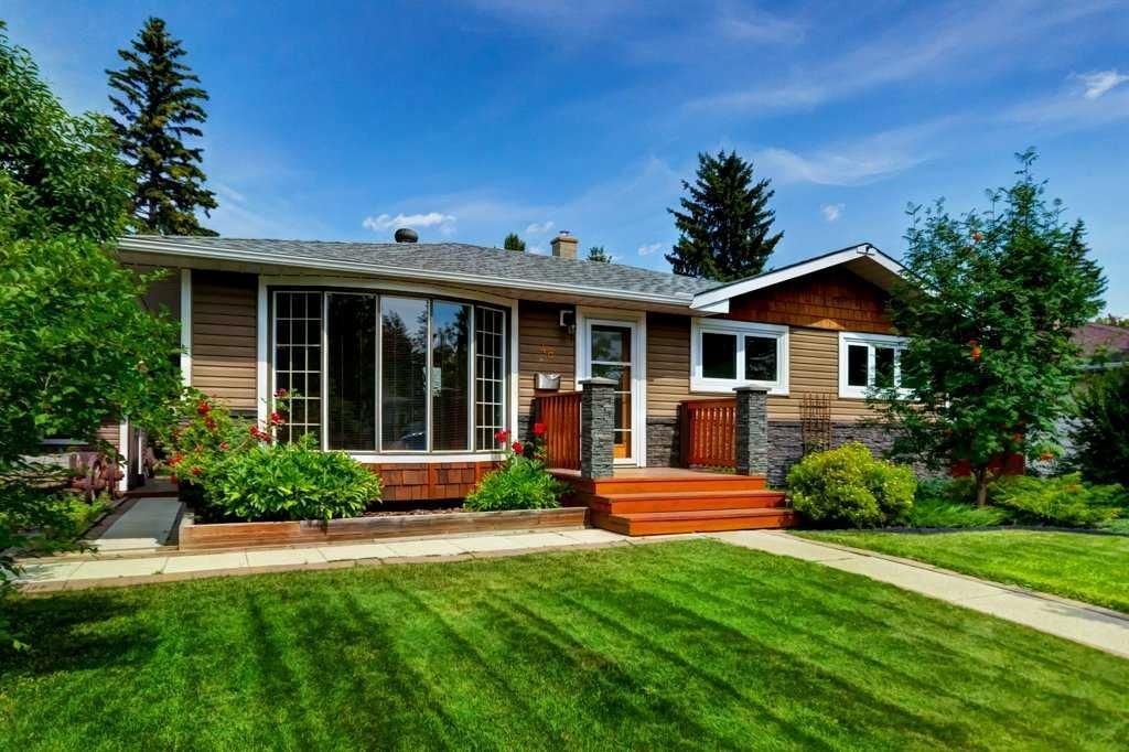 Single-story suburban house with a brick porch, large windows, and a green lawn under a blue sky