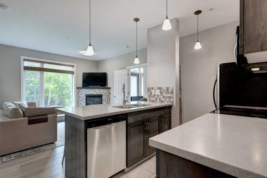 Modern kitchen with dark cabinets, light countertops, island, and pendant lights