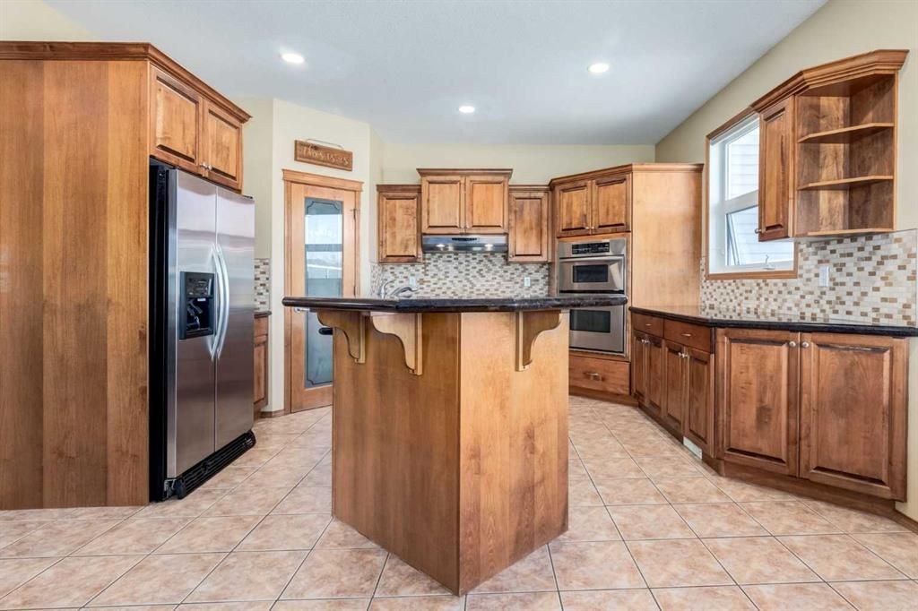 Bright kitchen with wood cabinets, stainless steel appliances, tile floor, and a central island