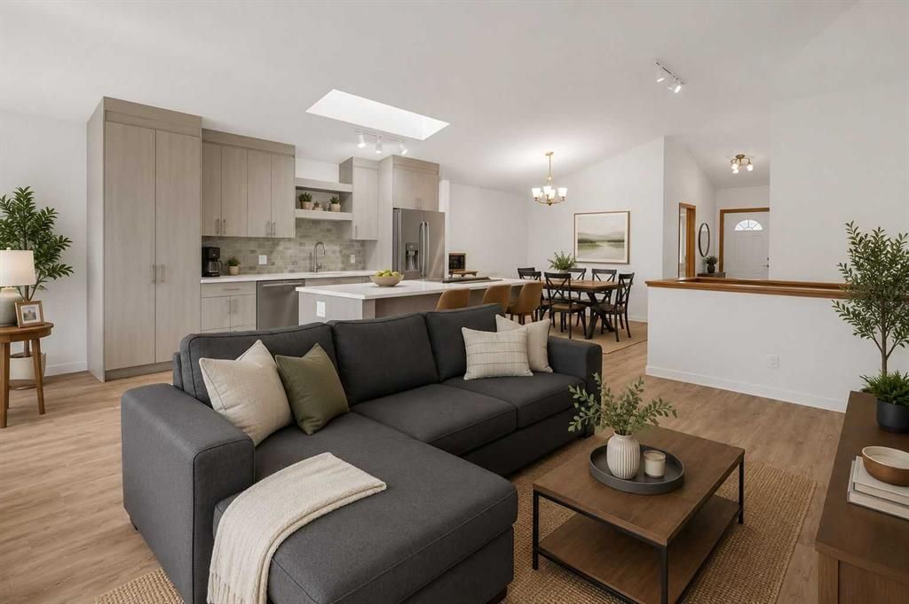 Bright modern living room with gray sectional, coffee table, kitchen, and dining area in open layout