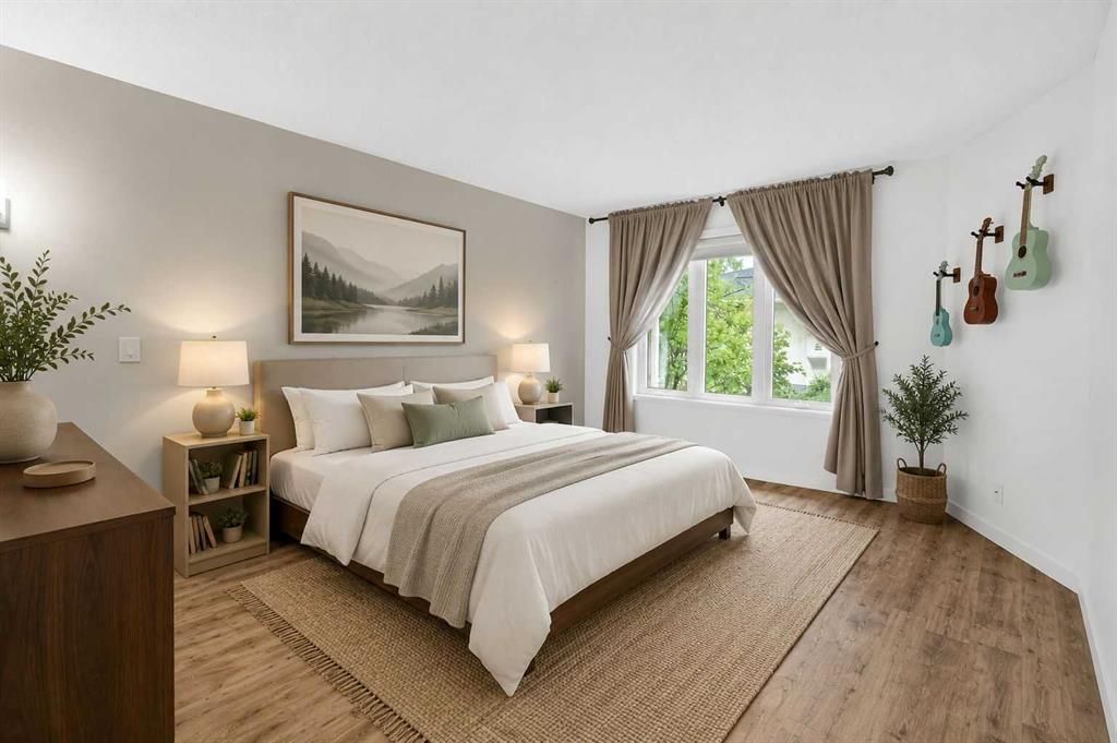 Cozy bedroom with a large bed, beige decor, wooden floor, and a window with curtains.