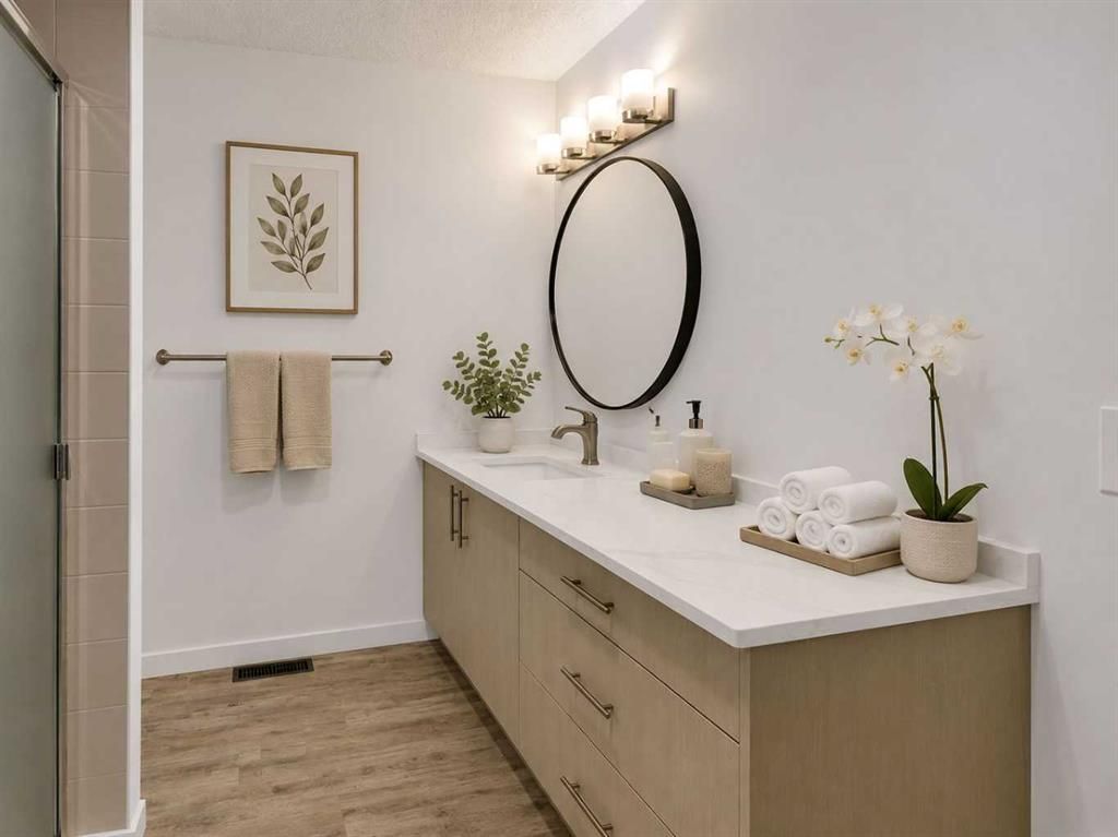 Modern bathroom vanity with mirror, wall sconces, beige cabinets, and white countertops