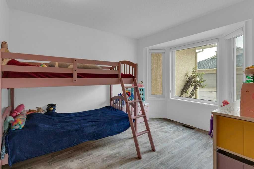 Children’s bunk bed in a bright bedroom with large windows and a small desk