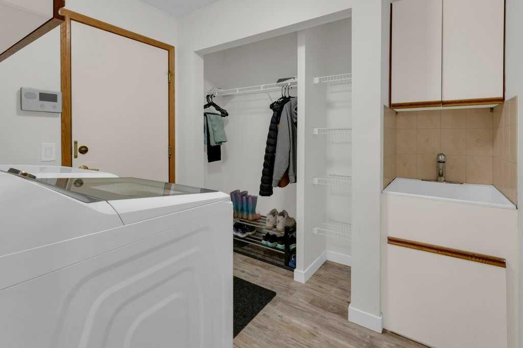 Laundry room with a washing machine, open closet, and white cabinets in a small hallway