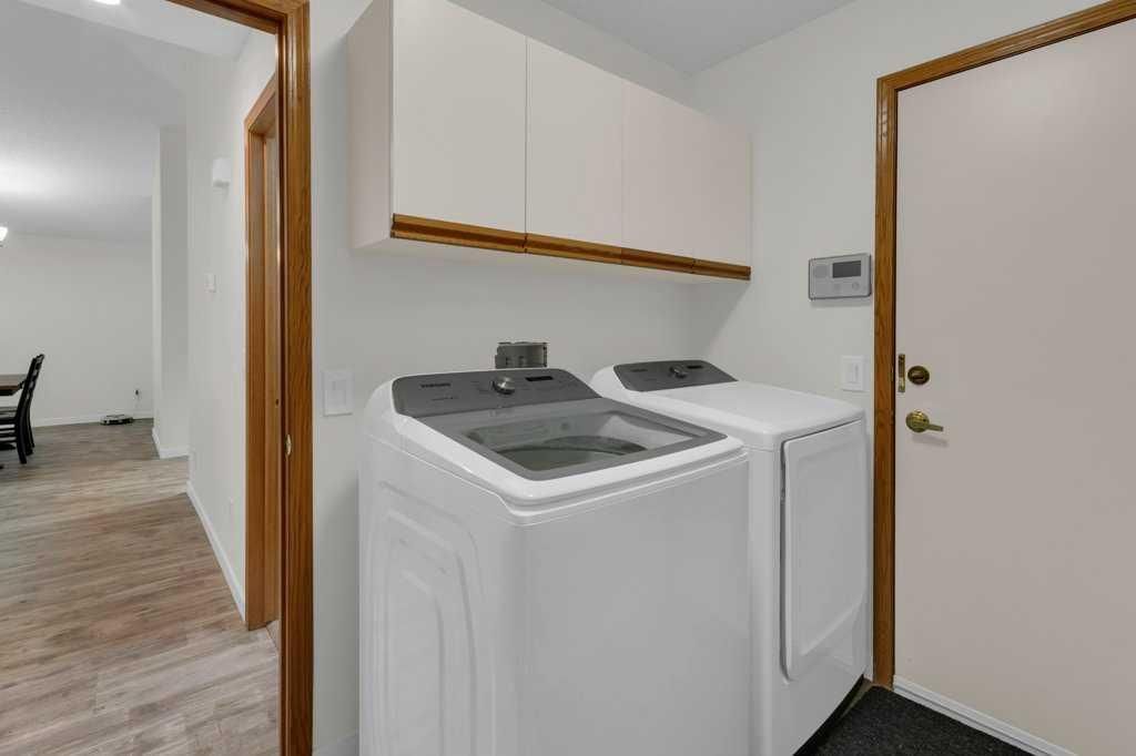 Laundry room with white washer and dryer beside a door and hallway view