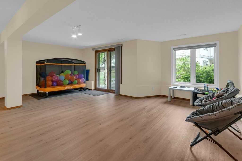 Bright empty room with wood floors, play tent, large windows, and seating by the wall