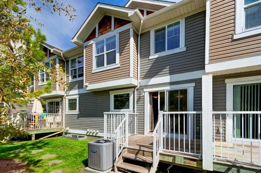 Townhouse apartment exterior with gray siding, white trim, and a small front porch by green lawn.