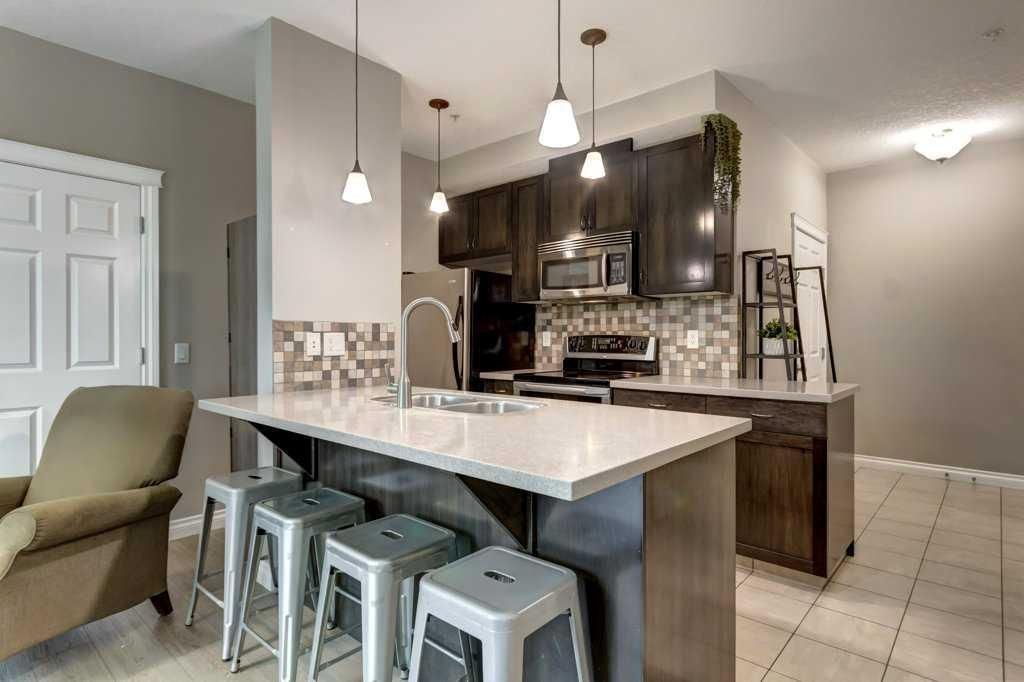Modern kitchen with white island, double sink, chrome faucet, and stainless steel appliances against tiled backsplash