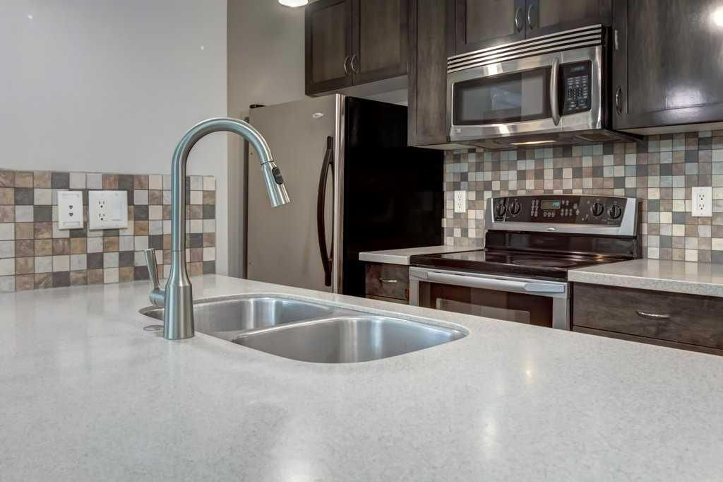 Modern kitchen with island sink, gray walls, tiled floor, and adjacent dining area