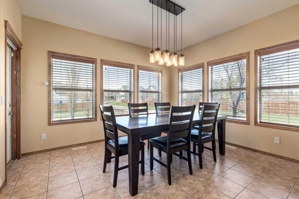 Dining room with black table and chairs, tiled floor, and large windows letting in natural light