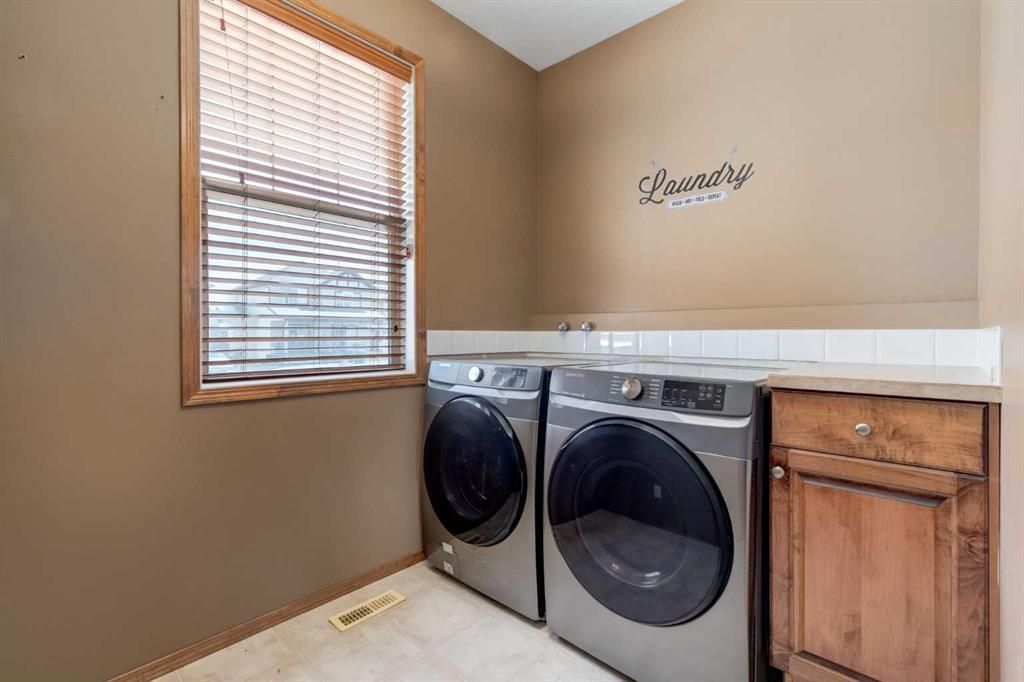 Laundry room with washer and dryer, wood cabinet, and window with blinds