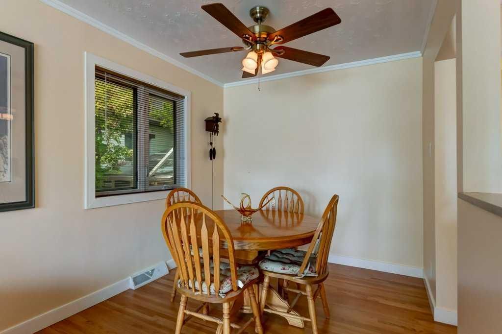 Dining nook with wooden table and chairs, ceiling fan, and window with blinds.