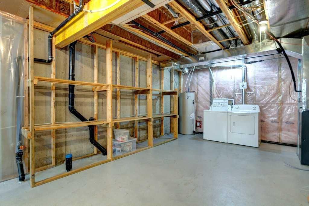 Unfinished basement with exposed framing, insulated walls, ductwork, and laundry machines on a concrete floor