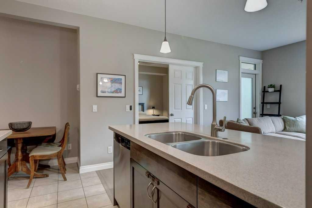 Modern kitchen with a large island, four stools, pendant lights, and an adjacent dining area.