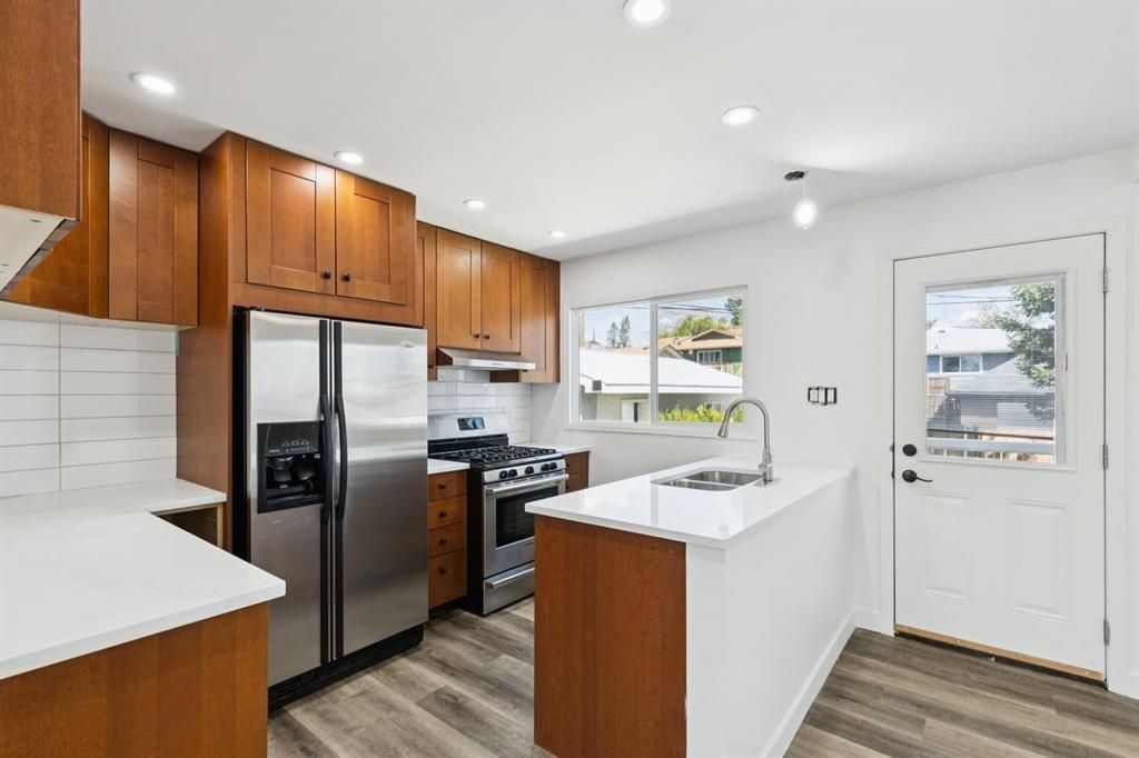 Bright modern kitchen with wood cabinets, white island, black appliances, and a glass back door