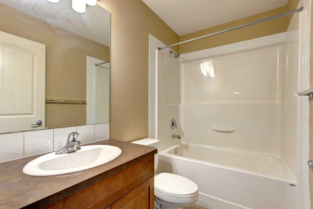 Bathroom with vanity sink, mirror, toilet, and white shower/tub combo with curtain rod.